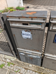 Briefkästen mit Rostschäden und hässlichen Schildern